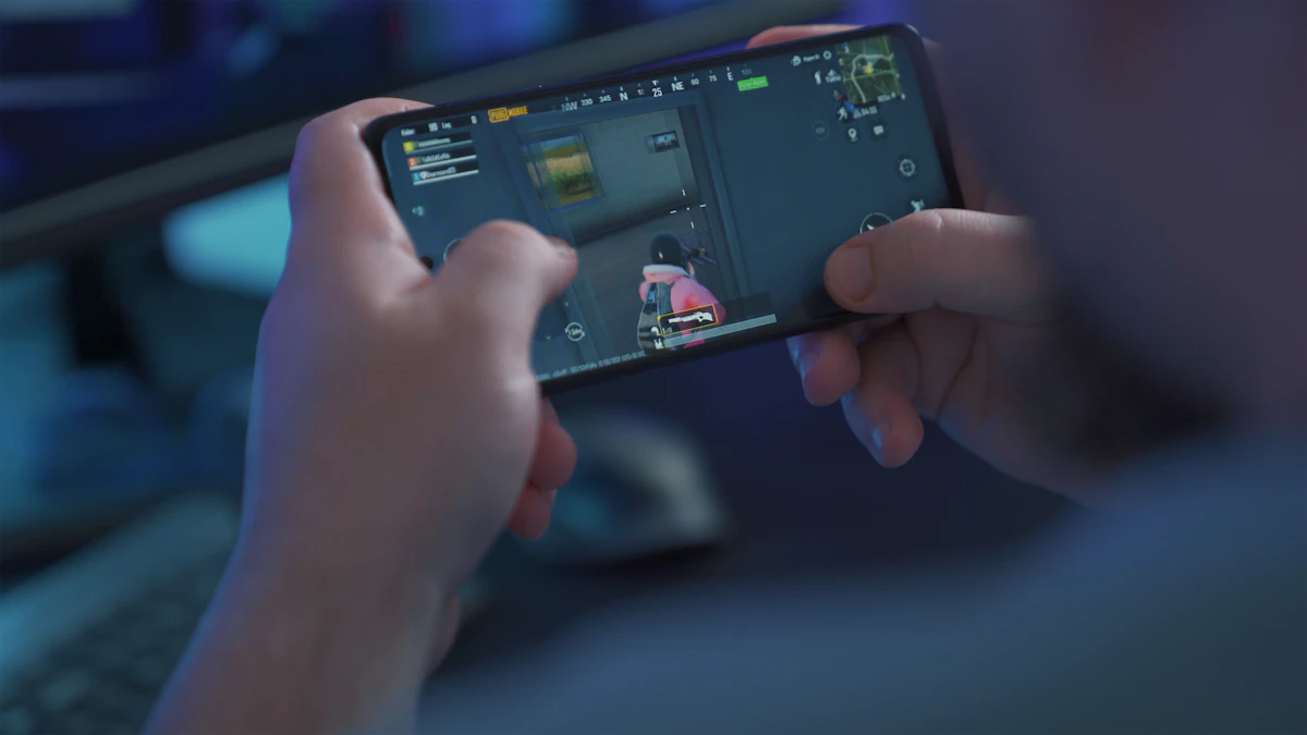 Pemain memegang smartphone saat bermain game mobile